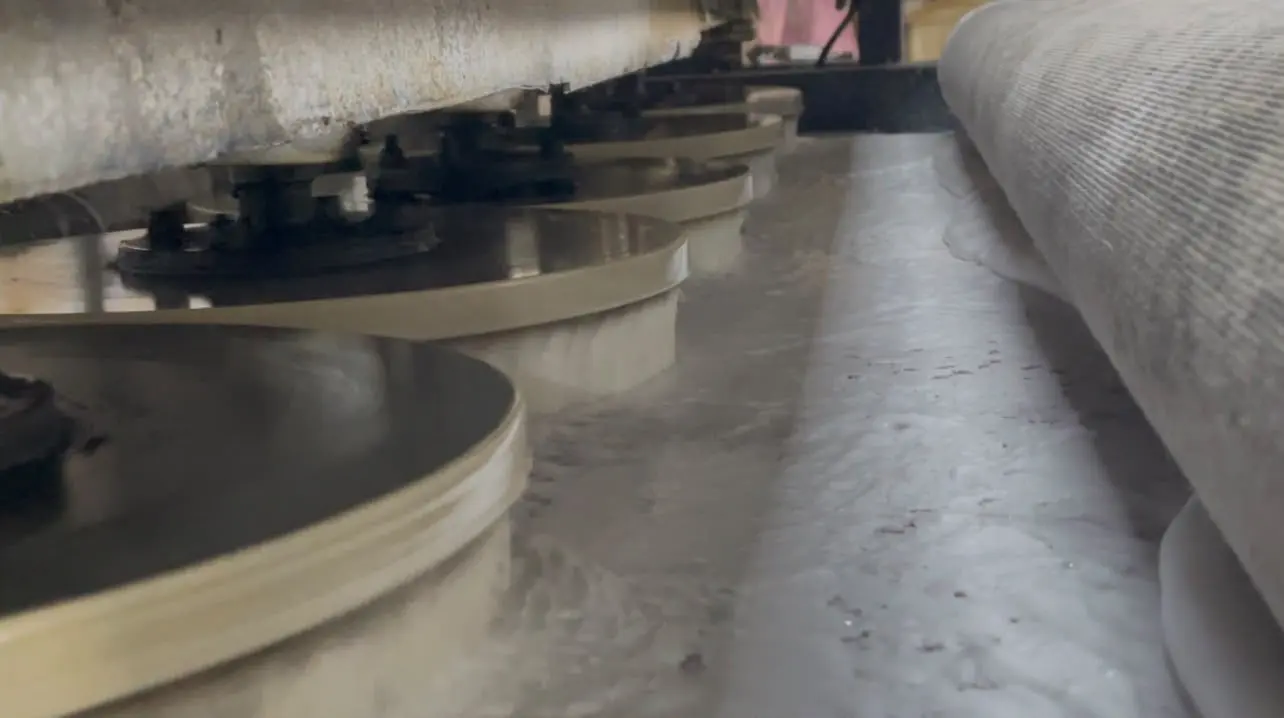 Fabrikadaki otomatik halı yıkama makinesinin döner fırçaları ve yıkanan halı